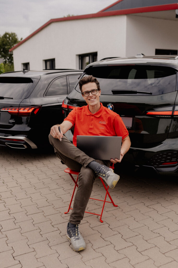 Autohaus Herr Schneider Mario sitzt vor Gebrauchtwagen